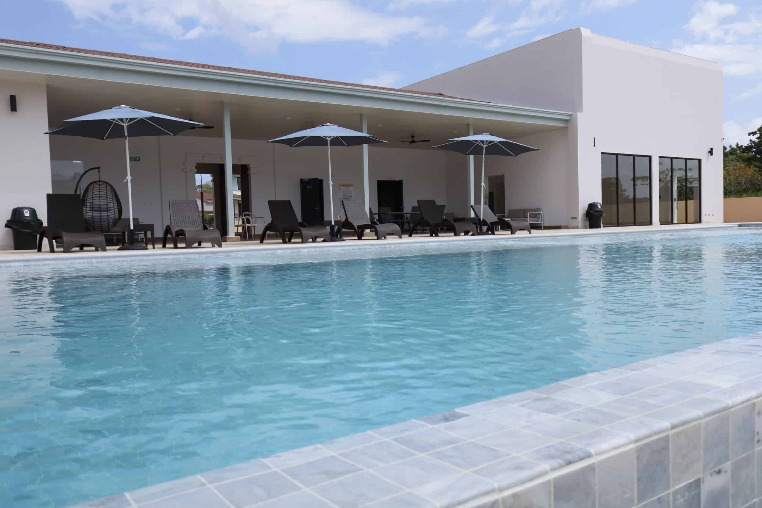 Piscina moderna con zona de descanso y sombrillas, ideal para disfrutar del verano en tu propia pisc.